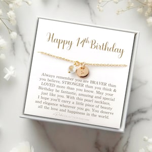 May include: A white gift box with a gold necklace inside. The box has a gold inscription that reads "Happy 14th Birthday". The necklace has a pearl charm and a gold charm with the letter "S". The text inside the box reads "Always remember you are BRAVER than you believe, STRONGER than you think & LOVED more than you know. May your Birthday be fantastic, amazing and special just like you. With this pearl necklace, I hope you'll carry a little piece of beauty and elegance wherever you go. You deserve all the love and happiness in the world."