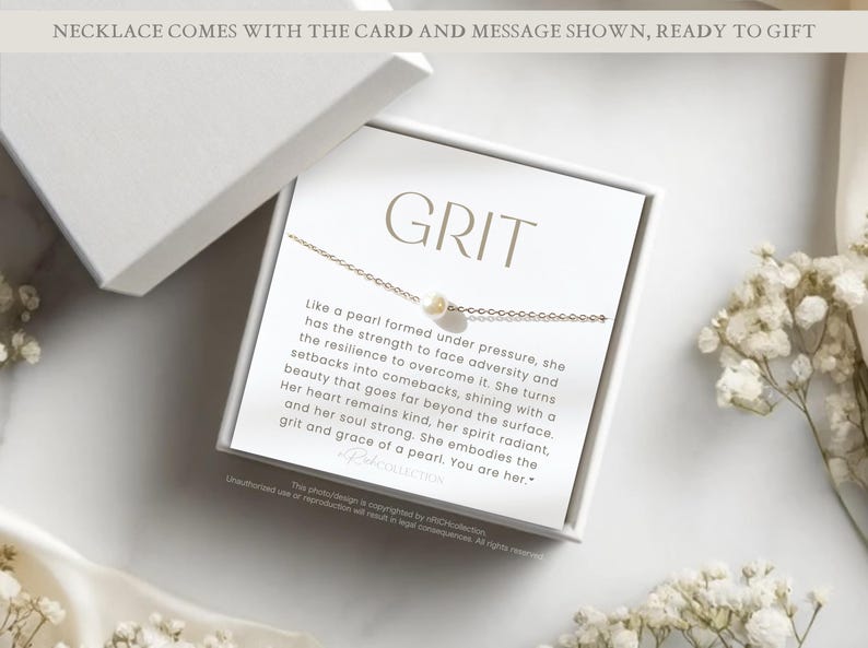 Op de afbeelding: Een witte cadeaudoos met een witte kaart erin. De kaart heeft een gouden ketting met een parelbedel en de tekst "GRIT" en een boodschap over de kracht en veerkracht van een parel.