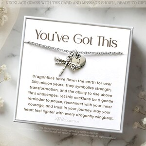 May include: A white card with the text "You've Got This" and a silver dragonfly necklace with a charm. The card includes a message about dragonflies symbolizing strength and transformation.