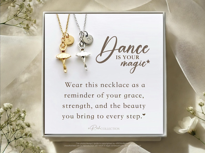 May include: A white gift box with a silver and gold necklace featuring a ballerina charm. The box has a message that reads "Dance is your magic*" and "Wear this necklace as a reminder of your grace, strength, and the beauty you bring to every step."
