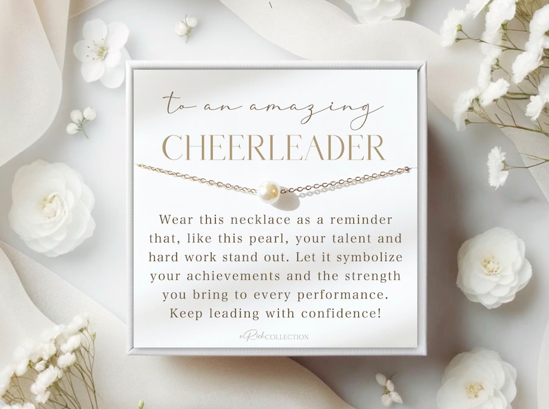 以下が含まれることがあります： 「to an amazing CHEERLEADER」と金色の文字で書かれた白いカード。カードは白い箱に入っていて、単一の真珠のペンダントが付いた金色のチェーンネックレスが入っています。カードには、「このネックレスを、この真珠のように、あなたの才能と努力が際立つことを思い出させてくれるものとして身につけてください。あなたの功績と、あらゆるパフォーマンスにもたらす力を象徴させてください。自信を持って、先頭に立ち続けてください！」と書かれています。