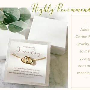 May include: A white jewelry box with a gold necklace featuring two intertwined hearts. The box is filled with white cotton and has a label that reads "Made with Love Jewelry". The connection of this two hearts necklace symbolizes the bond of two individuals that can never be undone. BROCHcollection etsy.com