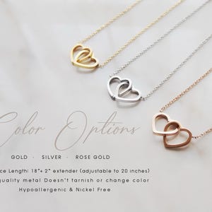 May include: Necklaces with interlocking heart pendants in gold, silver, and rose gold. The necklaces are displayed on a marble surface. The text "Color Options" is above the necklaces. The text below the necklaces reads "GOLD SILVER ROSE GOLD".