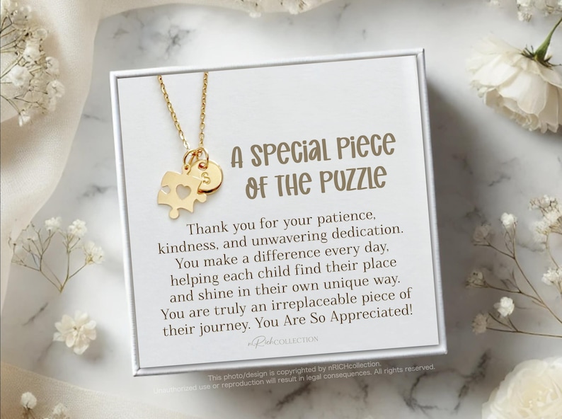 May include: A gold necklace with a puzzle piece charm and a small disc charm with the letter "S" on it. The necklace is displayed in a white box with a message that reads "A Special Piece of the Puzzle" and expresses gratitude for patience, kindness, and dedication. The message also states that the recipient makes a difference every day by helping children find their place and shine in their own unique way. The message concludes by saying that the recipient is an irreplaceable piece of the children's journey and is appreciated.