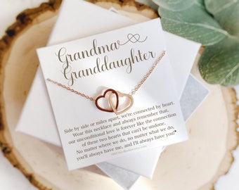 May include: A gold necklace with two interlocking heart charms on a white card with the text "Grandma Granddaughter" and a message about the connection between grandmothers and granddaughters.