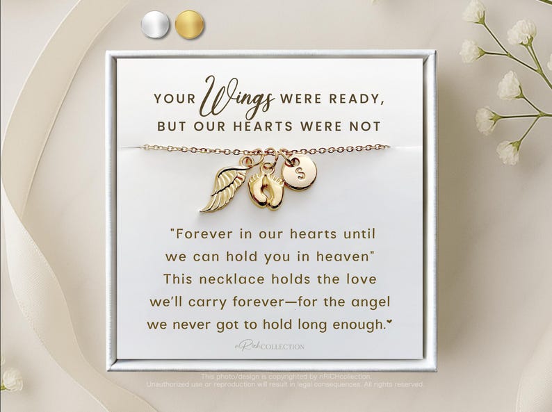 May include: A gold necklace with a charm of a small angel wing, a baby footprint, and a letter 'S' charm. The necklace is in a white box with the text "YOUR Wings WERE READY, BUT OUR HEARTS WERE NOT" and "Forever in our hearts until we can hold you in heaven" This necklace holds the love we'll carry forever-for the angel we never got to hold long enough."