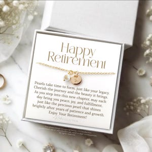 May include: A white gift box with a gold necklace inside. The box has a card that reads "Happy Retirement" and a message about pearls.