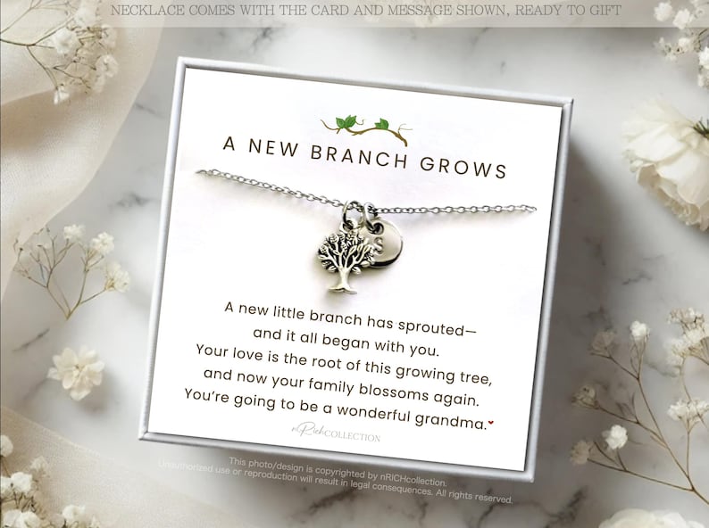 May include: A silver necklace with a tree pendant and a small charm, presented on a white card with the text "A New Branch Grows." The card includes a message about family and new beginnings, with floral accents.