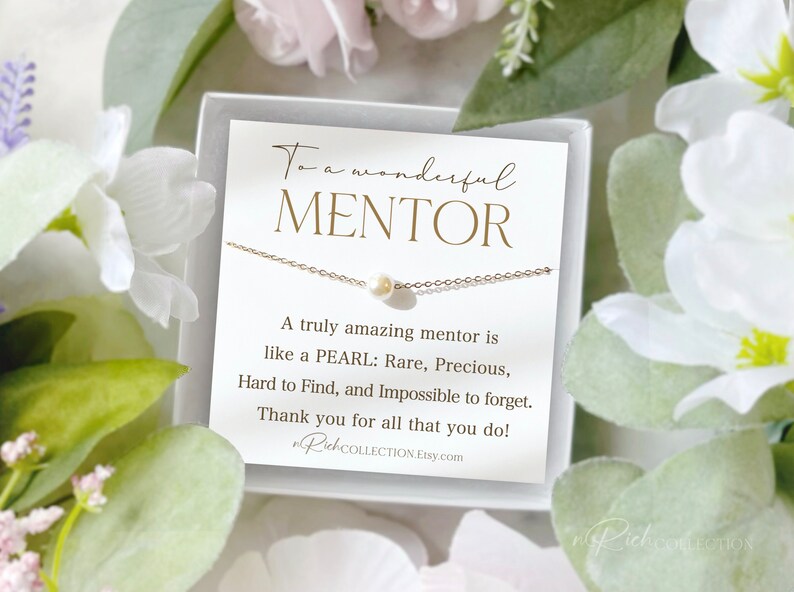 May include: A white card with gold lettering reads "To a wonderful MENTOR. A truly amazing mentor is like a PEARL: Rare, Precious, Hard to Find, and Impossible to forget. Thank you for all that you do!"  A delicate gold chain necklace with a single white pearl pendant is displayed on the card.