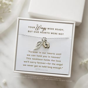May include: A silver necklace with a small angel wing charm and a charm of two tiny footprints. The necklace comes in a white box with a message that reads "Your wings were ready, but our hearts were not. Forever in our hearts until we can hold you in heaven. This necklace holds the love we'll carry forever - for the angel we never got to hold long enough."