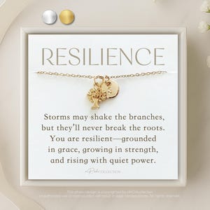 May include: A gold necklace with a small tree charm and a round charm with the word "RESILIENCE" on a white card with the text "Storms may shake the branches, but they'll never break the roots. You are resilient - grounded in grace, growing in strength, and rising with quiet power."