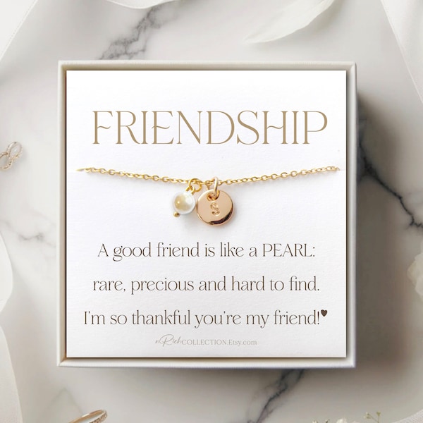 Peut inclure: Une boîte blanche contenant un collier en chaîne dorée avec un charme en perle et un charme en disque doré avec la lettre "S" dessus. La boîte a un fond blanc avec le texte "FRIENDSHIP" en noir en haut. Le texte sous le collier se lit comme suit : "Un bon ami est comme une PERLE : rare, précieux et difficile à trouver. Je suis tellement reconnaissant que tu sois mon ami !" 