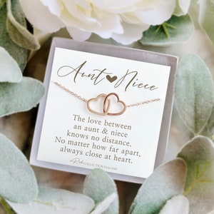 May include: A rose gold necklace featuring two interlocking heart pendants, presented in a gift box with a card. The card reads "Aunt & Niece" and includes a sentimental message about the bond between an aunt and niece.