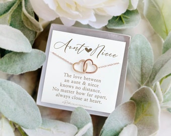 May include: A rose gold necklace featuring two interlocking heart pendants, presented in a gift box with a card. The card reads "Aunt & Niece" and includes a sentimental message about the bond between an aunt and niece.