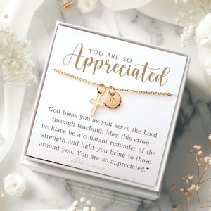 May include: A white gift box with a gold necklace inside. The necklace has a small gold cross charm and a gold initial charm. The box has a message that reads "You are so appreciated. God bless you as you serve the Lord through teaching. May this cross necklace be a constant reminder of the strength and light you bring to those around you. You are so appreciated."