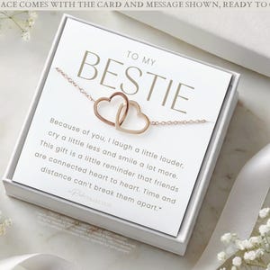 May include: A white gift box with a card that reads "To My Bestie" and a message about friendship. The card is accompanied by a rose gold necklace with two interlocking heart charms.