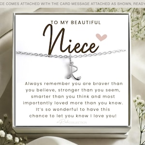 May include: A silver necklace with a charm that says "R" and a card that reads "To my beautiful niece" with a message about being brave, strong, smart, and loved.
