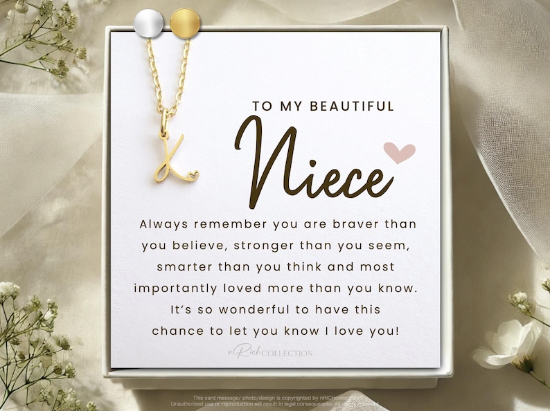 May include: A white card with a gold necklace featuring a cursive letter K pendant. The card reads "To my beautiful Niece" with a pink heart and a message about being brave, strong, smart, and loved.