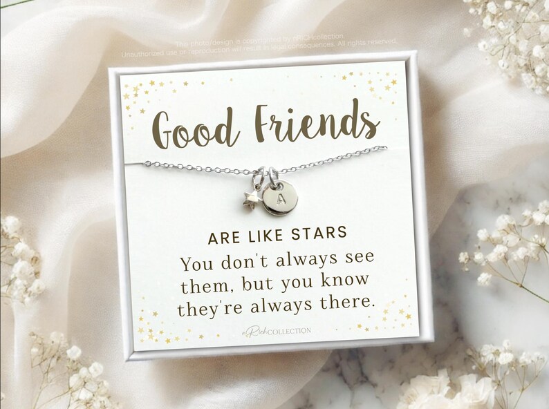 May include: A silver necklace with a star charm and a letter 'A' charm. The necklace is displayed on a white card with gold glitter and the text "Good Friends Are Like Stars You don't always see them, but you know they're always there."