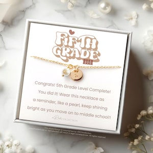 May include: A white gift box with a gold necklace inside. The necklace has a pearl charm and a charm with the letter "S". The box has a card that says "Congrats! 5th Grade Level Complete! You did it! Wear this necklace as a reminder, like a pearl, keep shining bright as you move on to middle school!!"