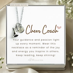 May include: A silver necklace with a charm of a cheerleader megaphone and a letter charm. The necklace is in a white box with a brown background and the text "Cheer Coach" and a message about guidance and passion.