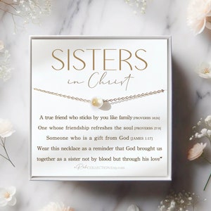 May include: A white box with a gold necklace and a pearl charm. The box has the text "SISTERS in Christ" and a message about friendship and faith.