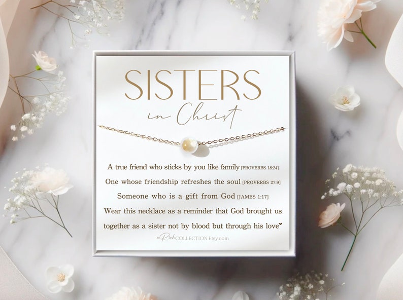 May include: A white box with a gold necklace and a pearl charm. The box has the text "SISTERS in Christ" and a message about friendship and faith.
