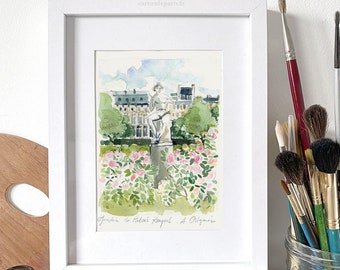 May include: A framed watercolor painting of a garden scene with a statue and pink roses. The painting is displayed with a stack of books about Paris, paintbrushes, and a jar of violet candies. The painting is signed "Jardins de Palais Royal A. Oilgainie".