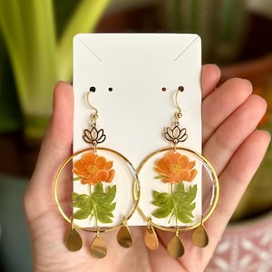 Pendientes dorados con una flor naranja: estilo botánico y elegancia boho. Estética cottagecore, mágicamente floral.