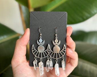 May include: Silver earrings with a crescent moon design and dangling clear quartz crystals.