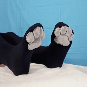 Szare pluszowe poduszki Mochi na łapach na czarnych skarpetkach do ud