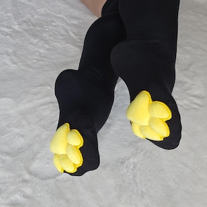 Medias altas hasta el muslo con almohadillas de pata de gato rellenas de mochi amarillo sobre negro