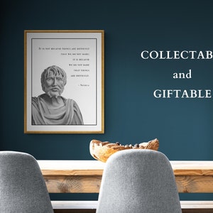 May include: A framed print with a quote by Seneca, a Roman philosopher, in black and white text on a white background. The quote reads "It is not because things are difficult that we do not dare; it is because we do not dare that things are difficult." The print is in a gold frame and is hanging on a teal wall. The text "COLLECTABLE and GIFTABLE" is written in white text on the wall.