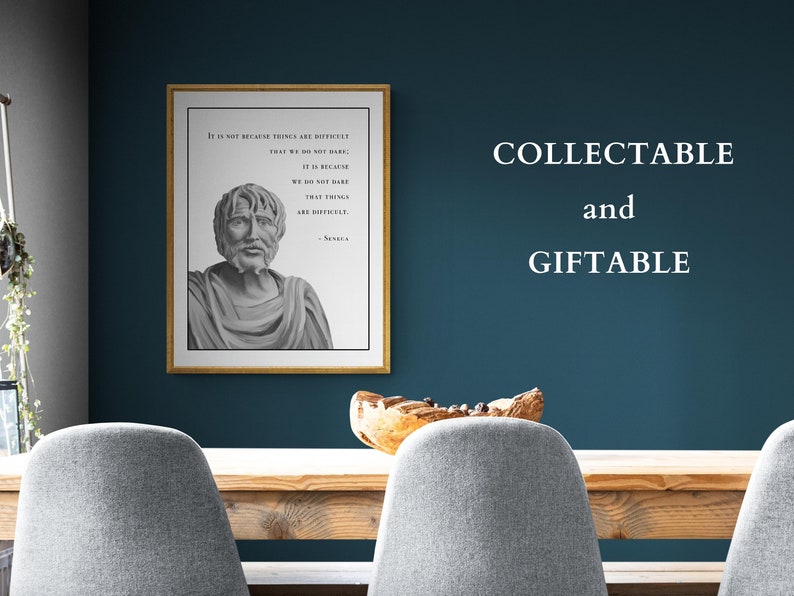 May include: A framed print with a quote by Seneca, a Roman philosopher, in black and white text on a white background. The quote reads "It is not because things are difficult that we do not dare; it is because we do not dare that things are difficult." The print is in a gold frame and is hanging on a teal wall. The text "COLLECTABLE and GIFTABLE" is written in white text on the wall.