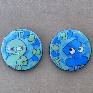 May include: Two round buttons with cartoon characters. One button features a green character with an angry expression, the text "TROT 20" in green. The other button has a blue character with a smiling face and the text "TROT 20" in green.
