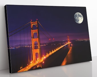 May include: A nighttime view of the Golden Gate Bridge in San Francisco, illuminated with lights. The bridge is lit up in orange and yellow, with the city lights visible in the background. A full moon is visible in the upper right corner of the image.