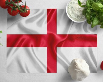 May include: A white table with a red cross flag on it. There are tomatoes, garlic, basil, and a bowl of white sauce on the table.