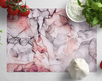 Peut inclure: Planche à découper de cuisine en verre trempé avec un motif marbré abstrait rose et gris. La planche est résistante à la chaleur et idéale pour couper, hacher et servir les aliments.