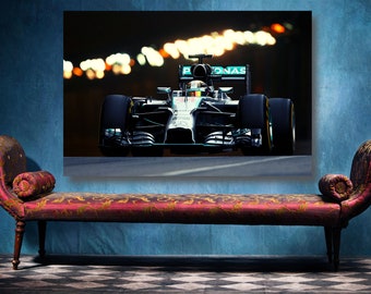 May include: A silver and black Formula 1 race car with the Petronas logo on the side, driving on a track at night with blurred lights in the background.