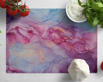 May include: Abstract art kitchen cutting board with a purple, blue, and gold design. The board is made of tempered glass and is heat resistant.