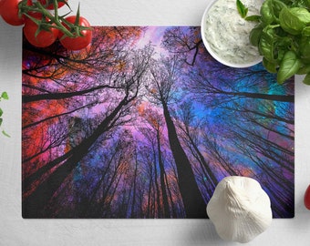 May include: A colorful cutting board with a design of a forest with trees reaching up to a starry sky. The sky is a mix of pink, purple, and blue with white stars.