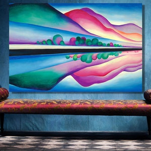 May include: Abstract painting of a landscape with a reflection of the mountains in a lake. The painting features a blue sky, green mountains, and a pink mountain range. The lake is a dark blue colour with a white line separating the water from the sky.