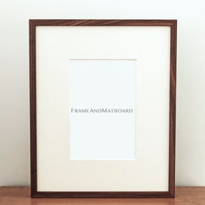 May include: A black walnut wood picture frame with a white mat and a white background. The frame is 11x14 inches.