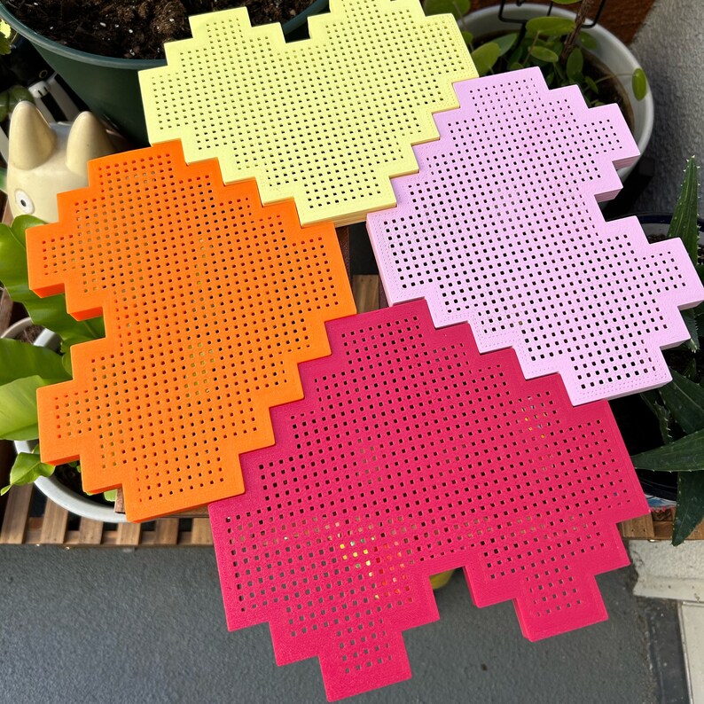 May include: Four heart-shaped pixelated foam tiles in yellow, orange, pink, and red.