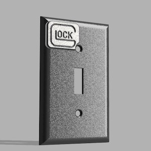 Puede incluir: Una tapa de interruptor de luz plateada con un interruptor negro y una pegatina plateada que dice "LOCK".