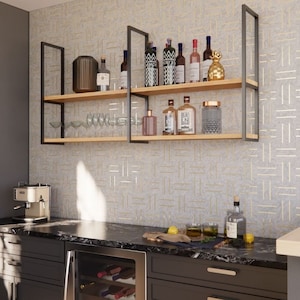 Può includere: Un mobile bar con cantinetta, mensole con bottiglie e un piano di lavoro con bevande. Le mensole sono sostenute da telai in metallo nero. La cantinetta è in acciaio inossidabile. Le pareti sono grigie e decorate.