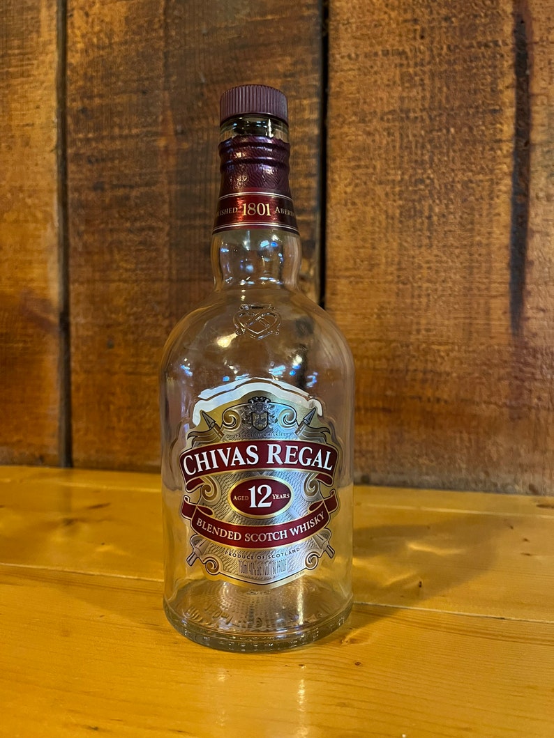 K&ouml;nnte beinhalten: Eine durchsichtige Glasflasche mit Chivas Regal 12 Jahre altem Blended Scotch Whisky. Die Flasche hat ein goldenes Etikett mit dem Chivas Regal Logo und den Worten "Aged 12 Years" und "Blended Scotch Whisky".