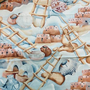 May include: Watercolor fabric featuring a Southwestern desert scene. The design includes adobe-style buildings, wooden ladders, and various pottery pieces in shades of brown, tan, and blue. The fabric has a light blue and white background.