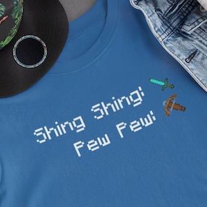 May include: A blue t-shirt with the text "Shing Shing! Few Few!" and pixelated images of a sword and pickaxe.