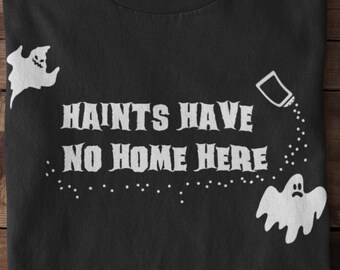 May include: Black t-shirt with a white graphic that says "HAINTS HAVE NO HOME HERE". The graphic includes two ghosts and a salt shaker.